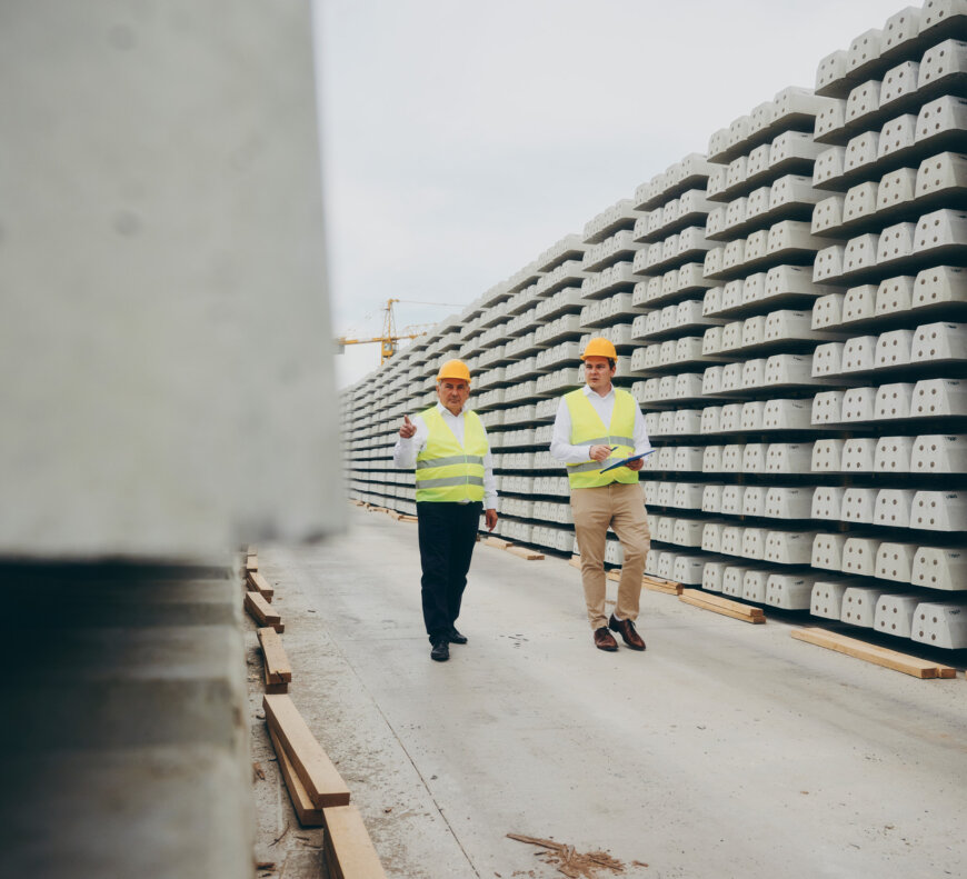 moll-rail-croatia-two-men-in-hard-hats-and-high-vis-vests-walking-past-stacked-concrete-sleepers moll-rail-croatia-two-men-in-hard-hats-and-high-vis-vests-walking-past-stacked-concrete-sleepers