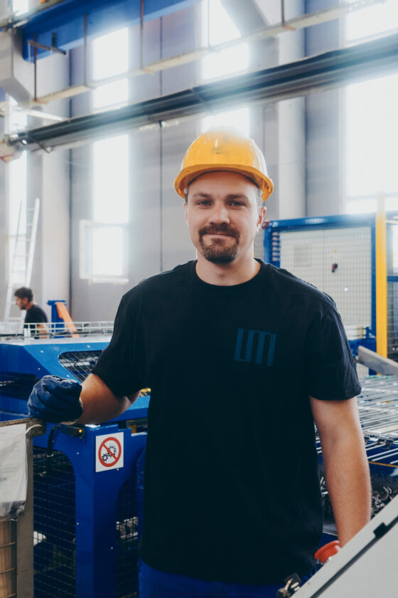 moll-rail-croatia-worker-wearing-a-yellow-hard-hat-standing-next-to-machinery-in-a-factory